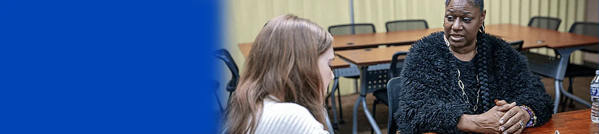 Photo of a Black woman speaking with a white woman in a conference room