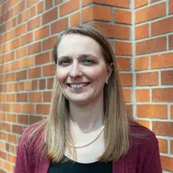 Photo of a smiling white woman posing in front of a brick wall